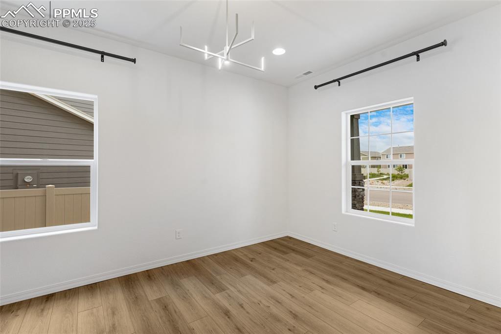 Image 10 of 50: Spare room with a chandelier, light wood-style flooring, and baseboards