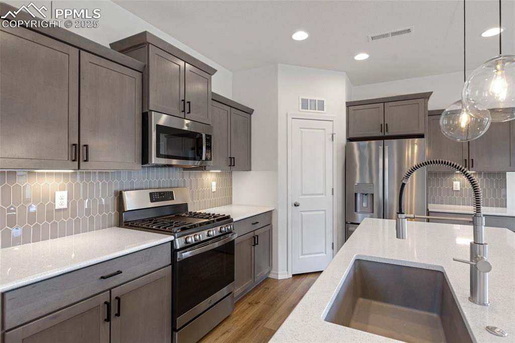 Image 15 of 50: Kitchen featuring appliances with stainless steel finishes, a sink, light w