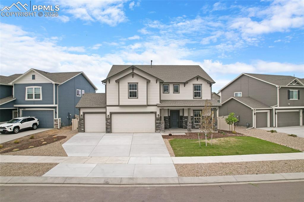 Image 2 of 50: View of front of home with covered porch, an attached garage, driveway, roo