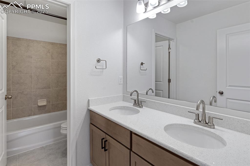 Image 26 of 50: Bathroom featuring double vanity, tile patterned floors, toilet, and shower