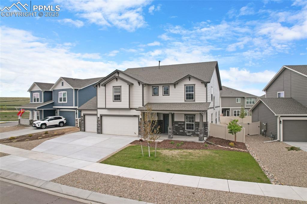 Image 3 of 50: View of front of property with stone siding, a porch, driveway, a garage, a