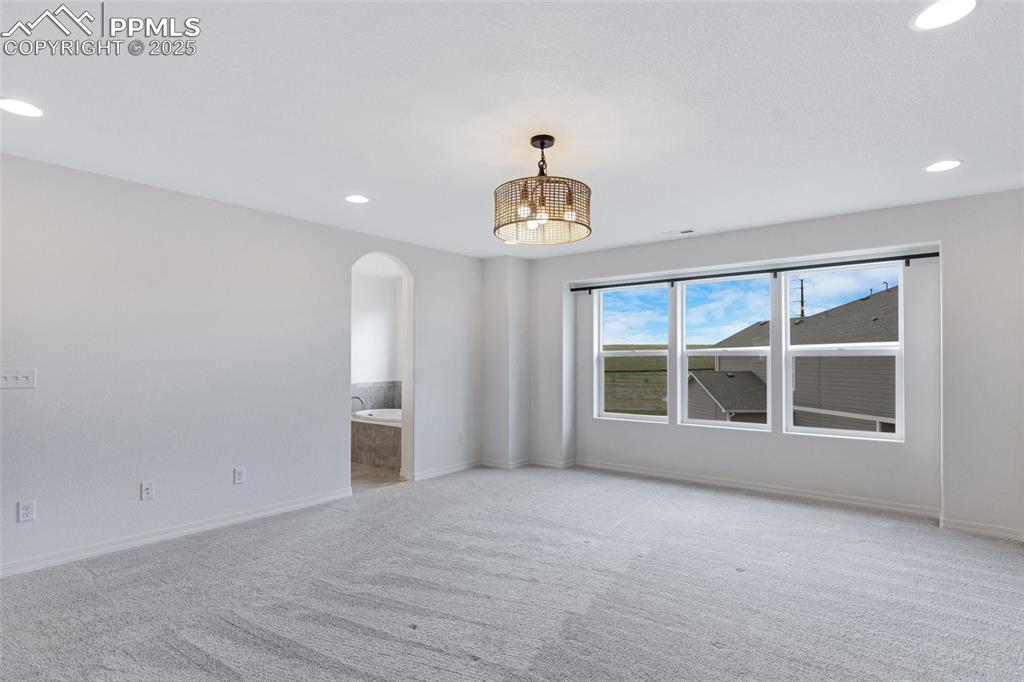 Image 32 of 50: Carpeted empty room featuring arched walkways, baseboards, and recessed lig
