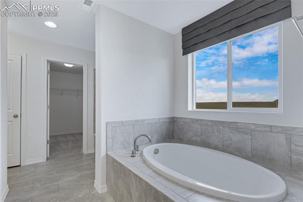 Image 34 of 50: Full bathroom featuring a garden tub, a walk in closet, baseboards, and rec