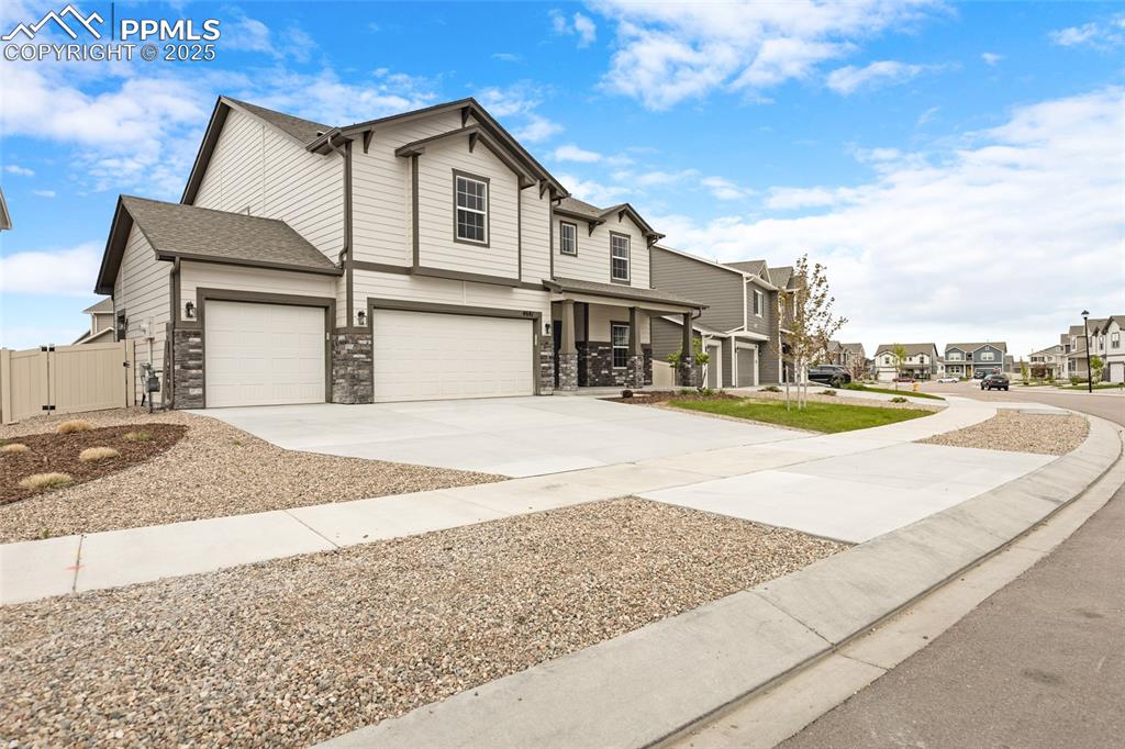Image 5 of 50: View of front facade featuring a residential view, driveway, stone siding,