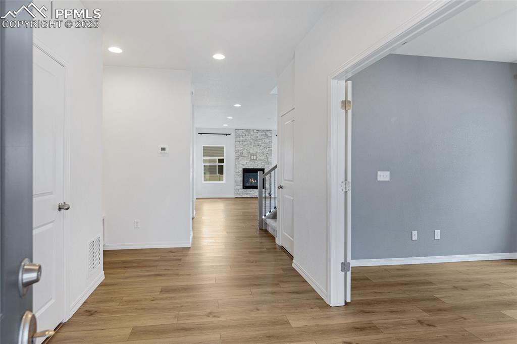 Image 8 of 50: Hallway with light wood finished floors, baseboards, and recessed lighting