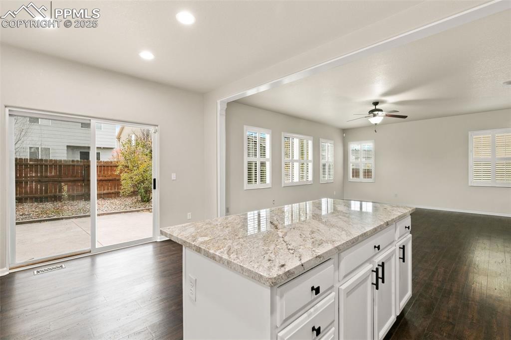 Image 11 of 27: Kitchen featuring a kitchen island, white cabinetry, healthy amount of natu