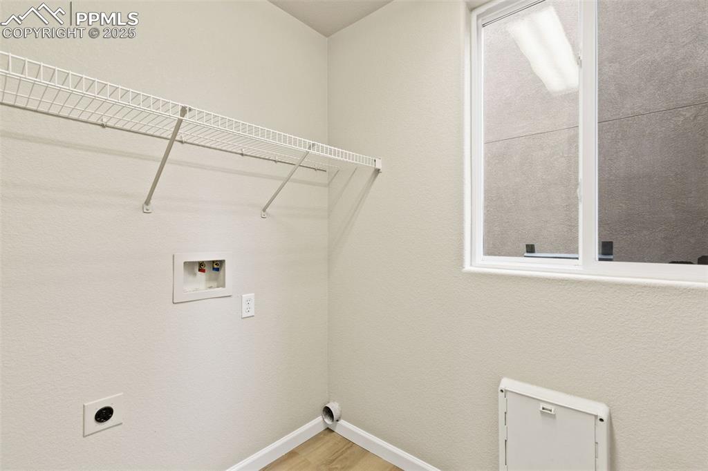 Image 14 of 27: Laundry room featuring light wood finished floors, hookup for an electric d
