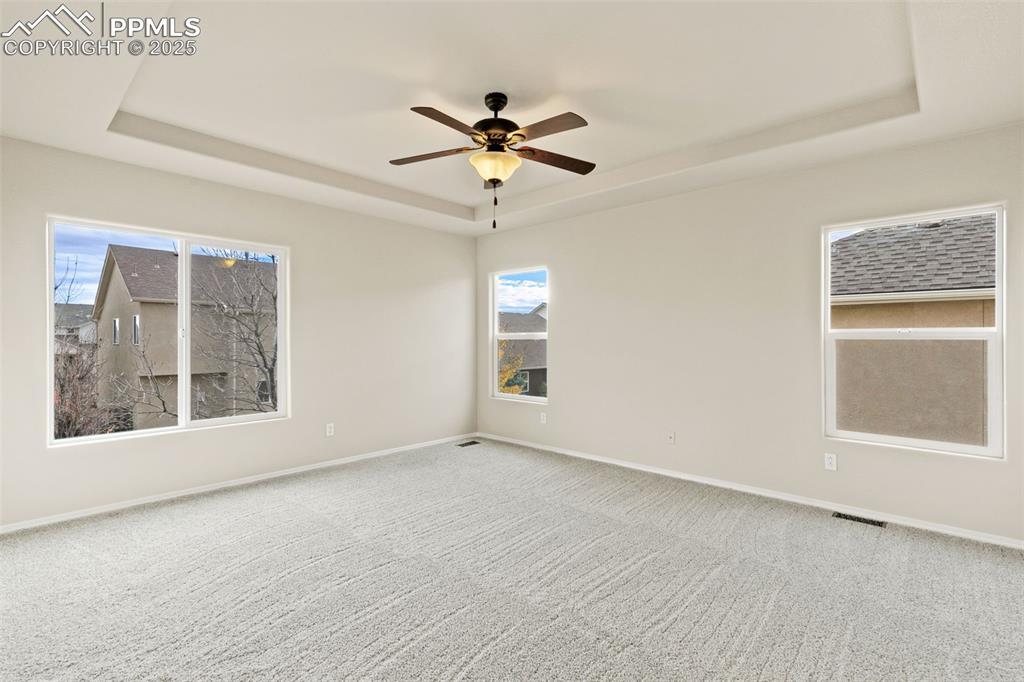 Image 15 of 27: Carpeted spare room featuring a raised ceiling and ceiling fan