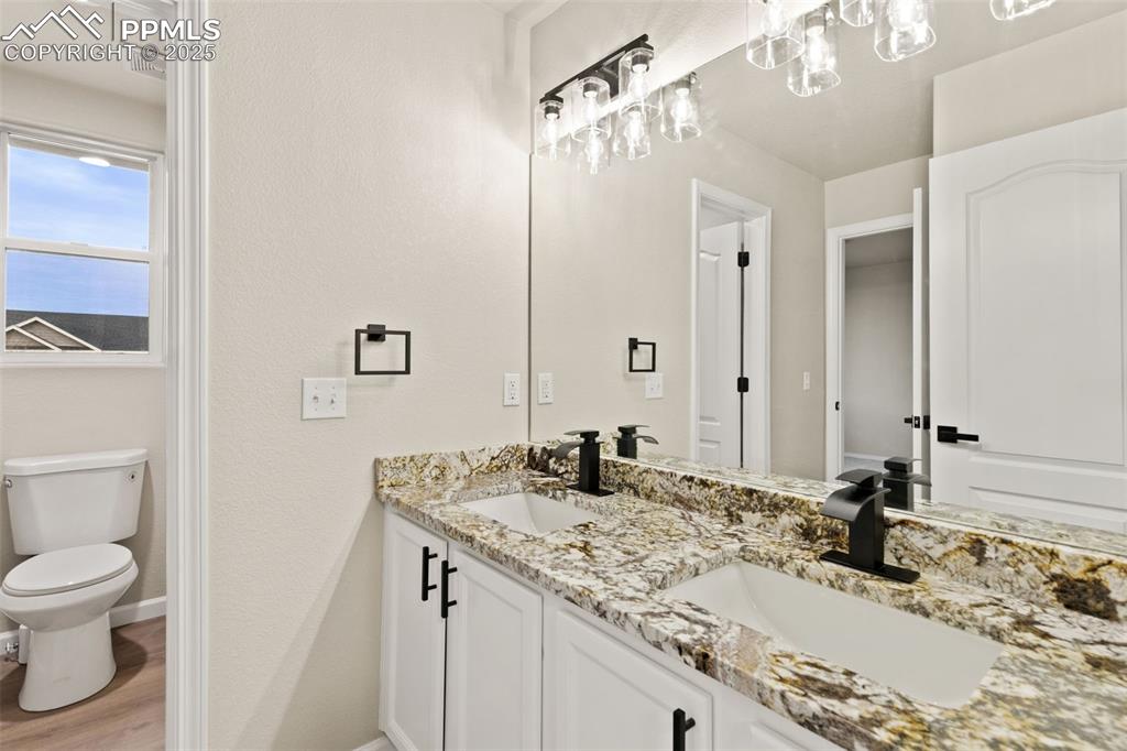 Image 18 of 27: Bathroom with double vanity and light wood-style flooring