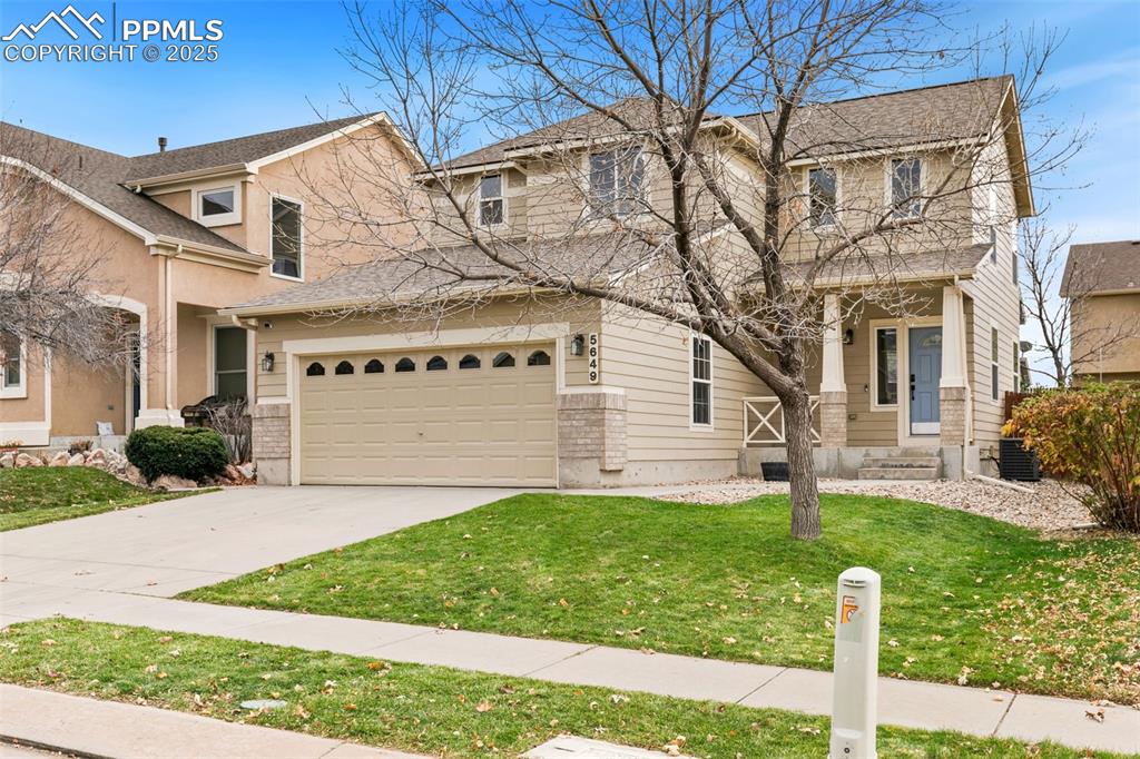 Image 2 of 27: Traditional home with a front lawn, covered porch, driveway, and roof with 
