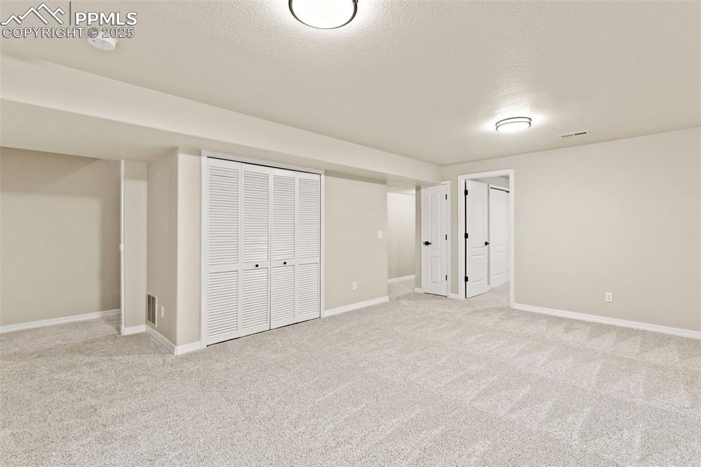 Image 21 of 27: Finished below grade area featuring a textured ceiling and light carpet