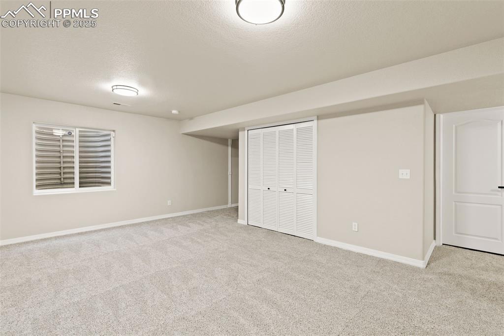 Image 22 of 27: Basement with light colored carpet and a textured ceiling