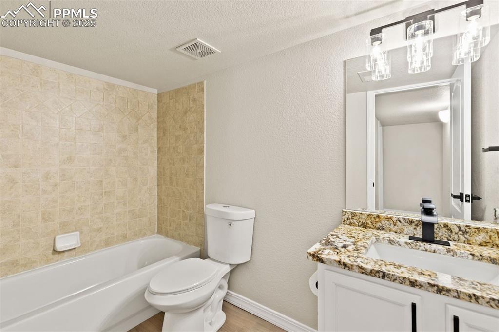 Image 25 of 27: Bathroom featuring a textured wall, vanity, a textured ceiling, and bathtub