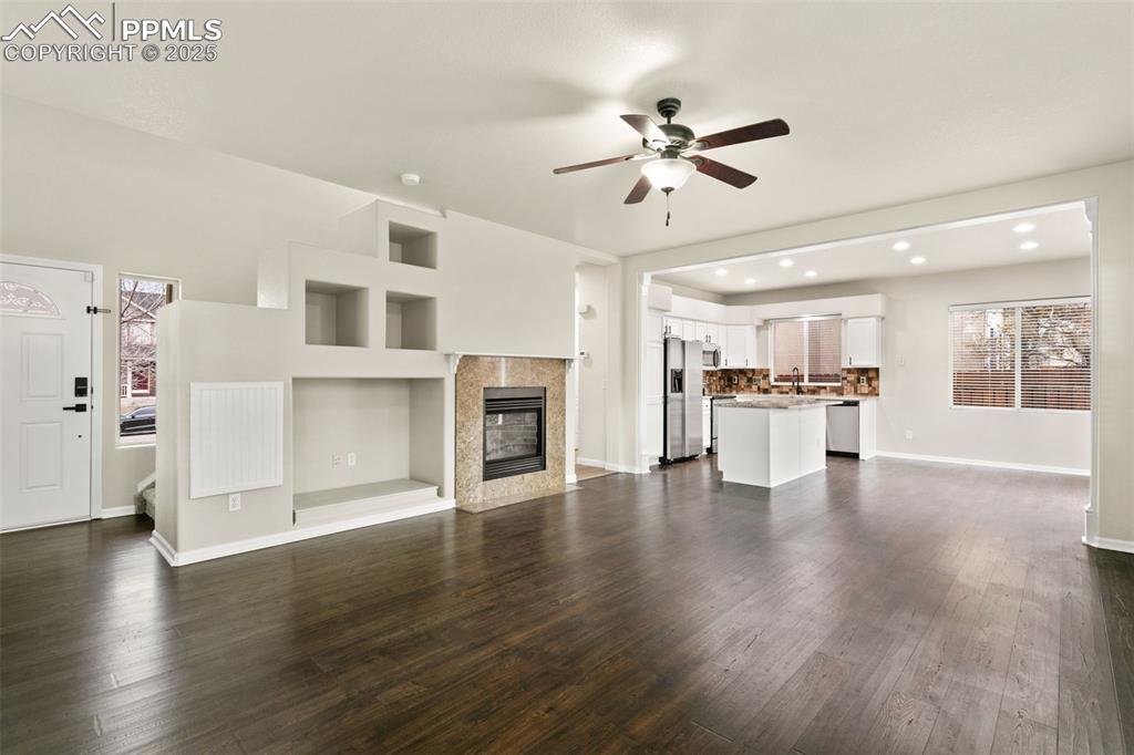 Image 4 of 27: Unfurnished living room featuring a tile fireplace, dark wood finished floo