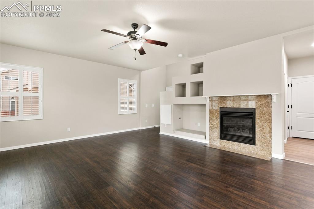 Image 5 of 27: Unfurnished living room featuring built in shelves, dark wood-type flooring