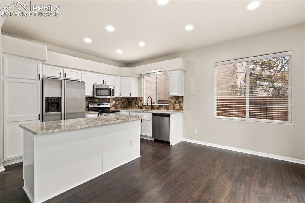 Image 8 of 27: Kitchen with white cabinets, tasteful backsplash, recessed lighting, applia