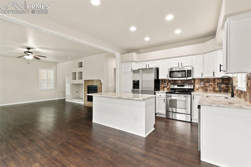 Image 9 of 27: Kitchen with decorative backsplash, appliances with stainless steel finishe