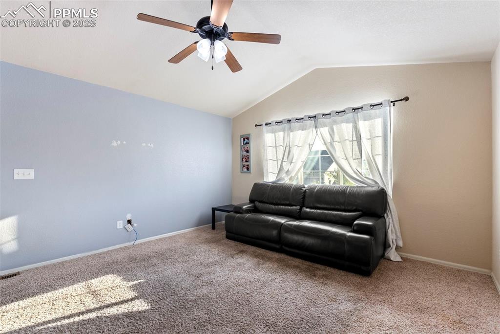 Image 16 of 46: Carpeted living room with vaulted ceiling and ceiling fan