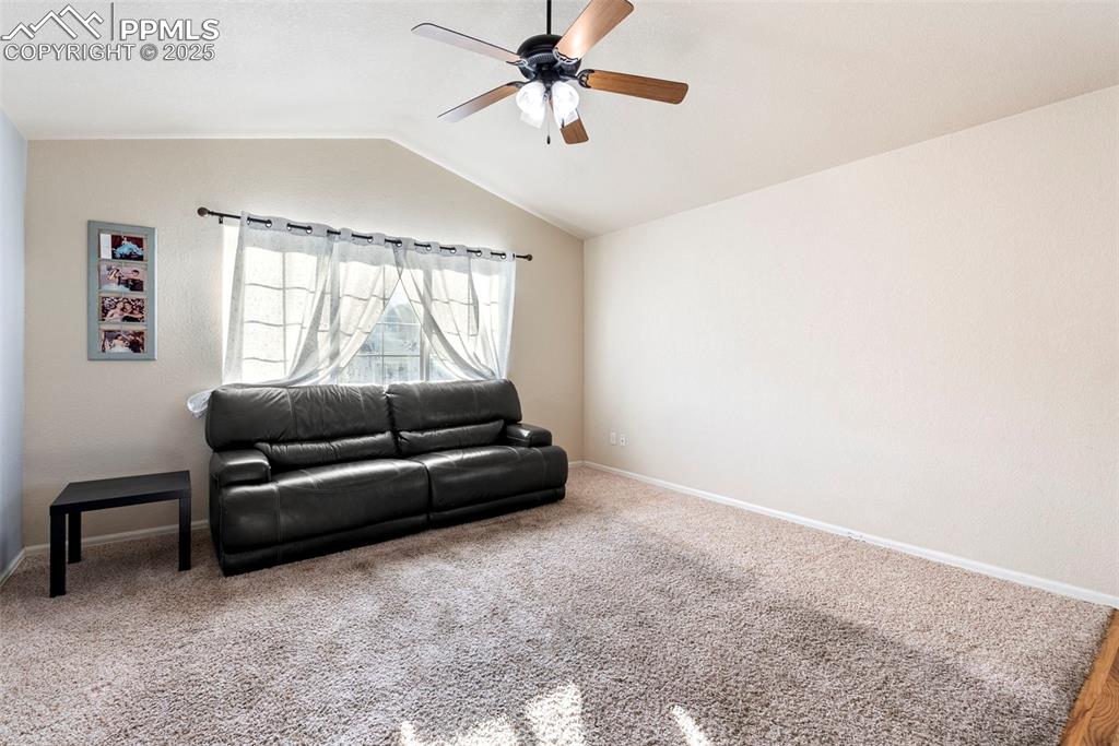 Image 17 of 46: Carpeted living room with vaulted ceiling and ceiling fan