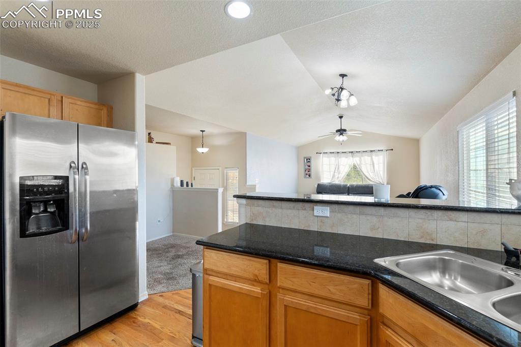 Image 18 of 46: Kitchen with stainless steel fridge, lofted ceiling, light wood-type floori