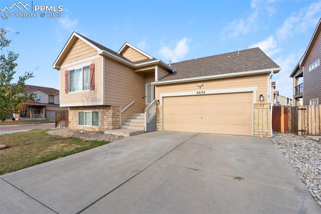 Image 2 of 46: View of front of home with stone siding, driveway, a shingled roof, and a g