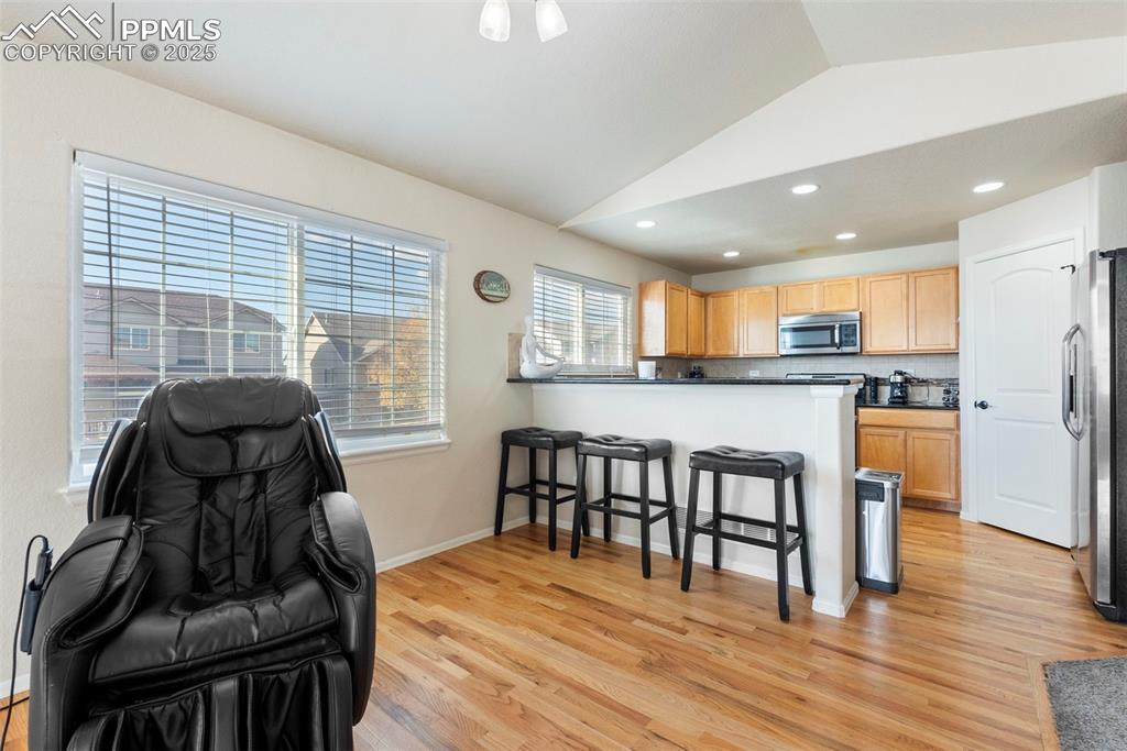 Image 22 of 46: Kitchen featuring lofted ceiling, a kitchen breakfast bar, light wood-style