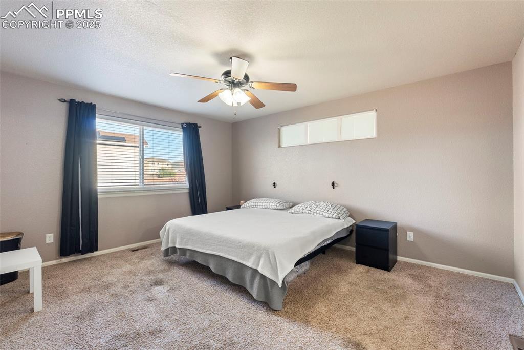 Image 24 of 46: Bedroom with carpet, ceiling fan, and a textured ceiling