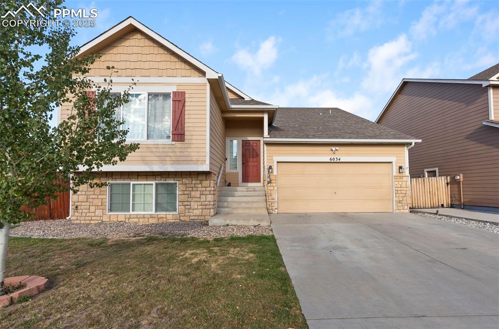 Image 3 of 46: View of front of home featuring stone siding, concrete driveway, a garage, 