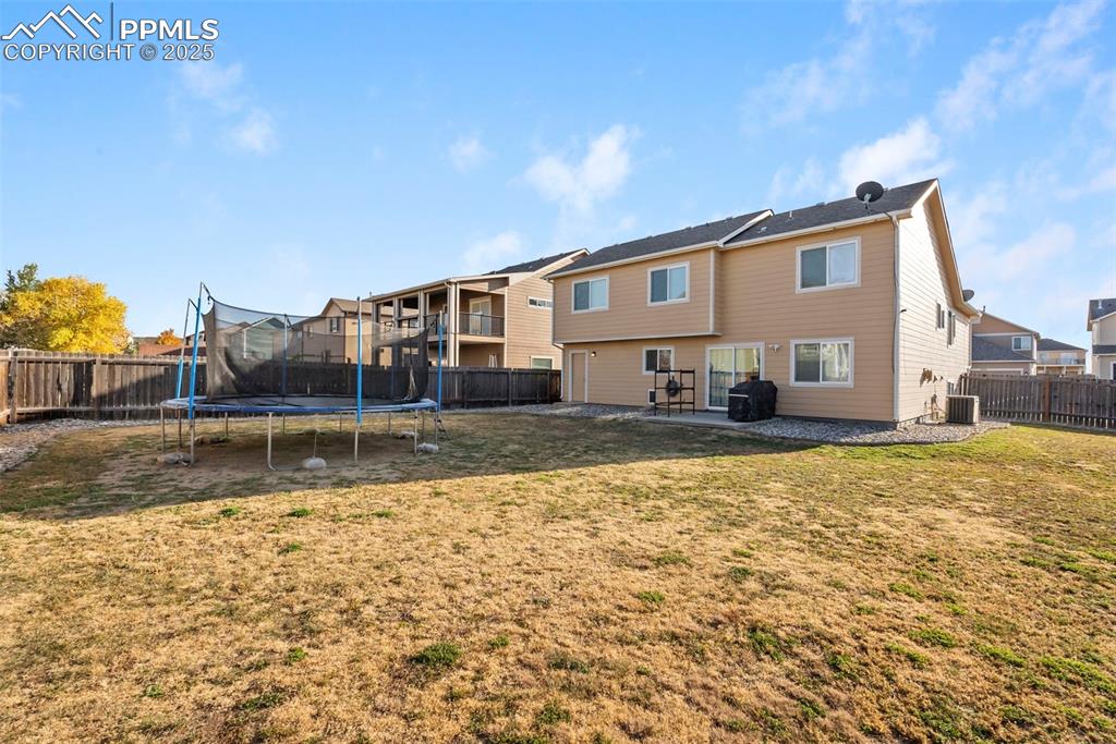 Image 9 of 46: Back of property with a patio, a fenced backyard, and a trampoline