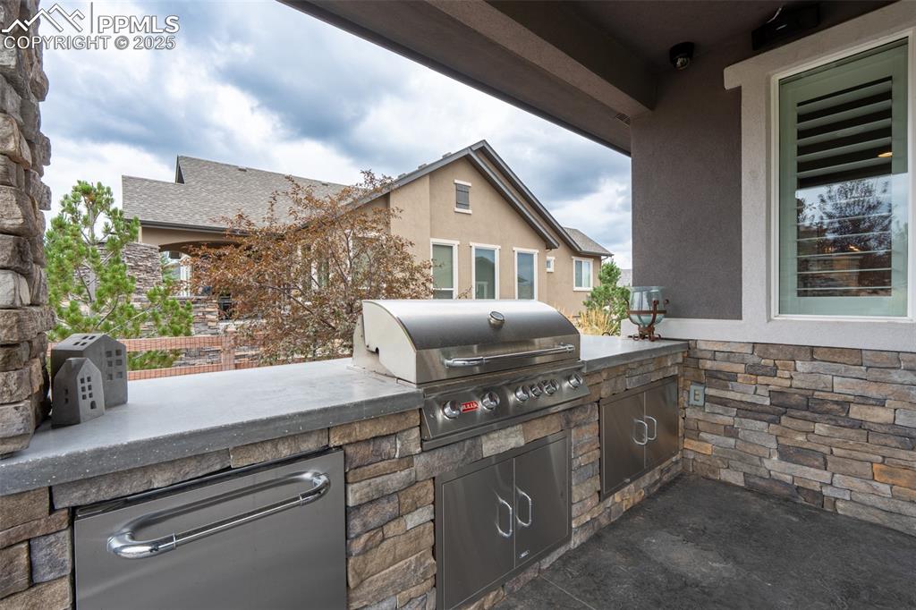 Image 39 of 50: Back patio with gas fireplace and built in stainless steel grill