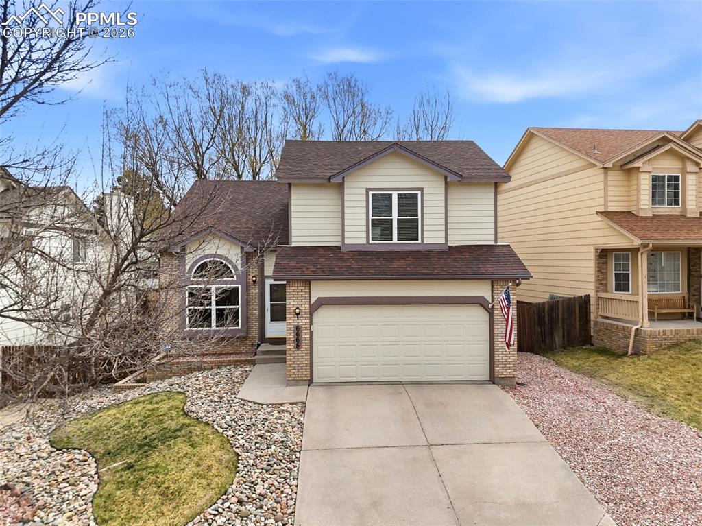 Caption: Traditional home featuring concrete driveway, roof with shingles, an attached garage, and brick sidi