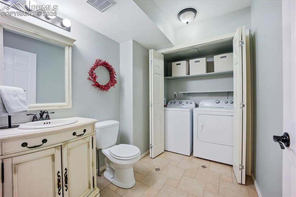 Image 14 of 46: Bathroom with vanity,  tile flooring, and a closet for washer and dryer