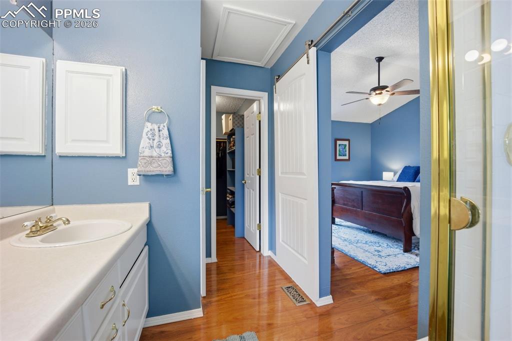 Image 21 of 46: Bathroom with vanity, ceiling fan, light wood-style floors, and a textured 