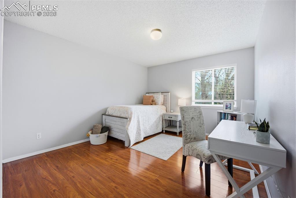 Image 25 of 46: Bedroom with a textured ceiling, a desk, and wood finished floors