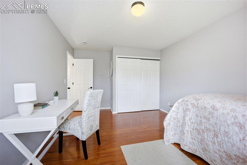 Image 27 of 46: Bedroom with a desk, wood finished floors, a closet, and a textured ceiling