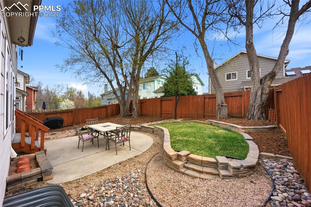 Image 34 of 46: Fenced backyard with a patio and outdoor dining space