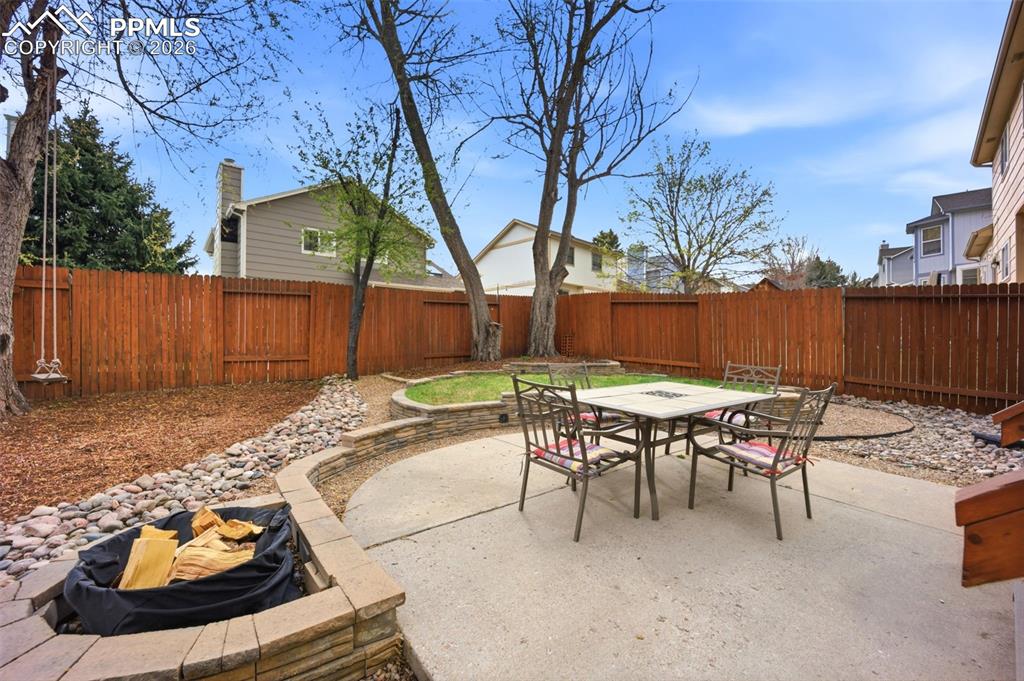 Image 35 of 46: Fenced backyard with a patio area and outdoor dining space