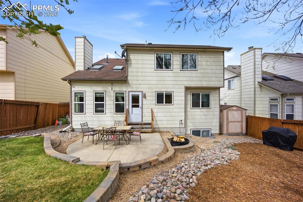 Image 36 of 46: Rear view of house with a patio, an outdoor fire pit, a shed, and landscapi