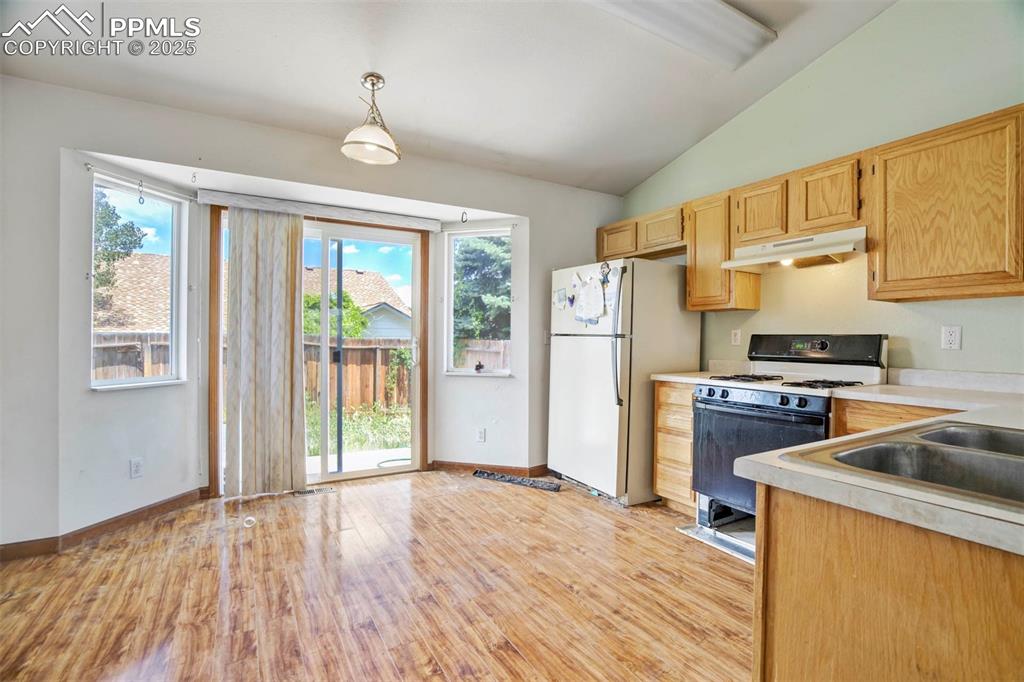 Image 12 of 37: Kitchen featuring white appliances, under cabinet range hood, light wood fi