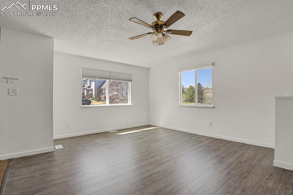 Image 4 of 19: Living room with a ceiling fan, plenty of natural light, dark wood finished