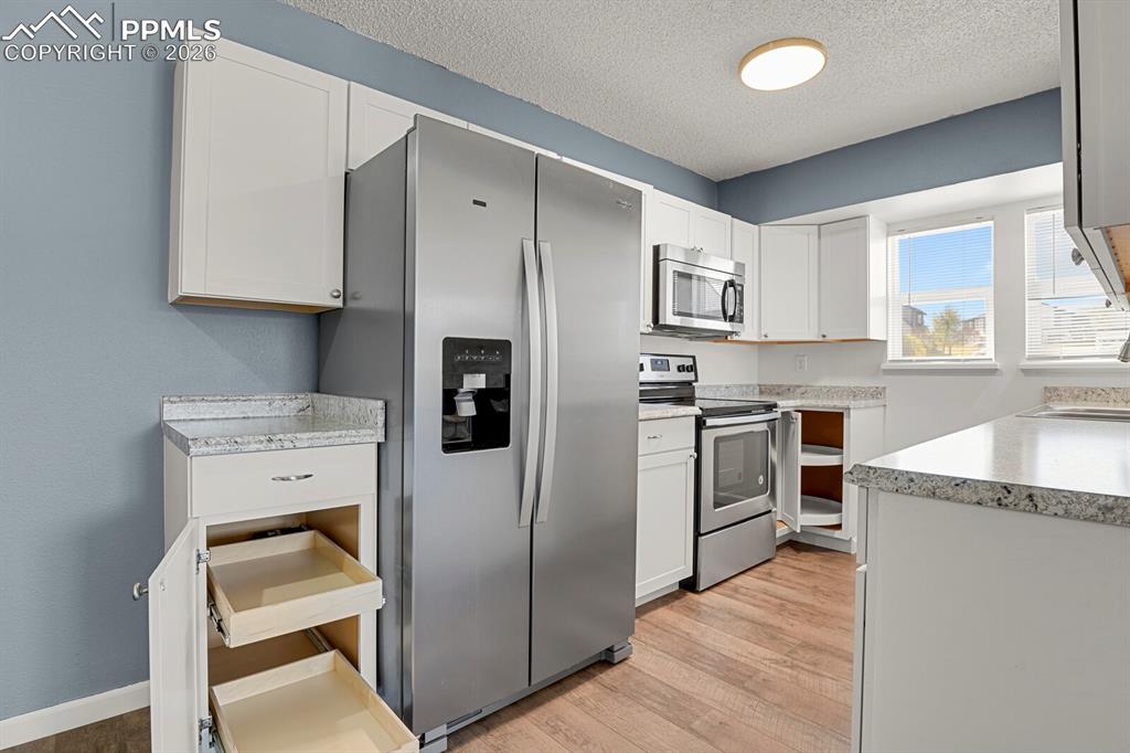 Image 6 of 19: Kitchen featuring Pull-out Draweres, stainless steel appliances, light coun