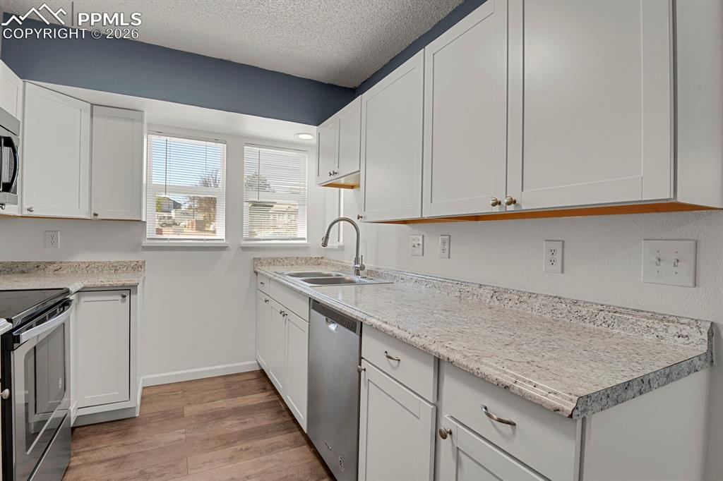 Image 7 of 19: Kitchen with stainless steel appliances, white cabinets, Lots of light