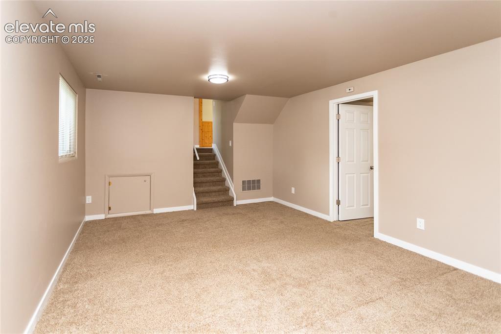 Image 28 of 46: Family room looking towards bedroom door and stairs to main level