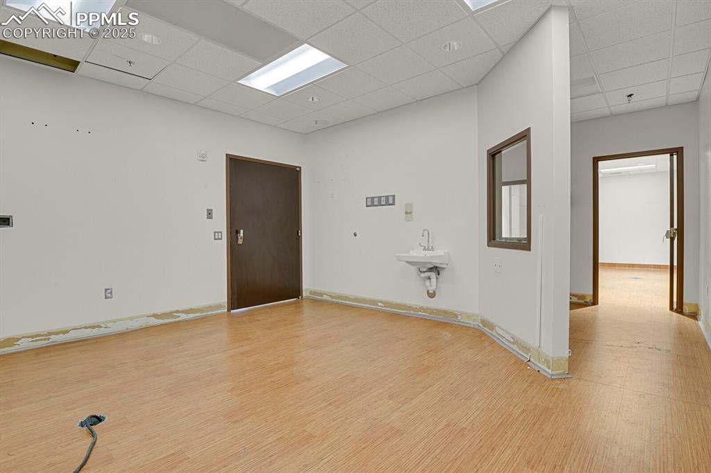 Image 10 of 50: Empty room featuring a paneled ceiling, light wood-style floors, and a pend