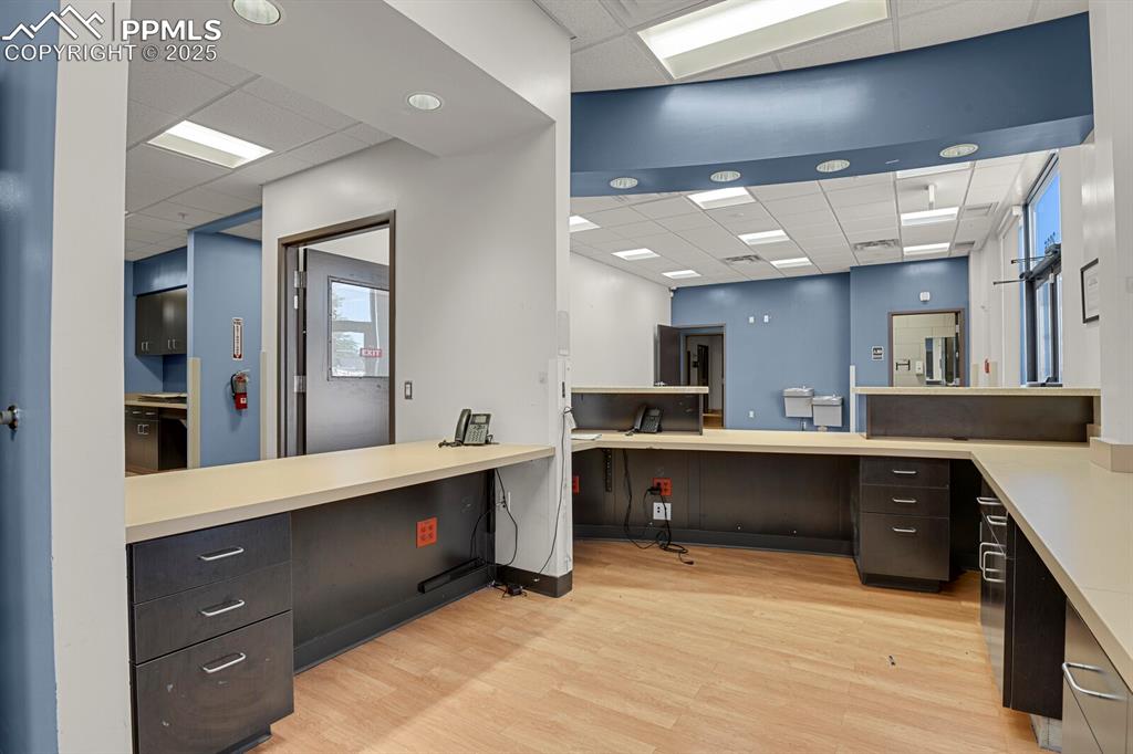 Image 16 of 50: Office with a drop ceiling, light wood-style flooring, and built in desk