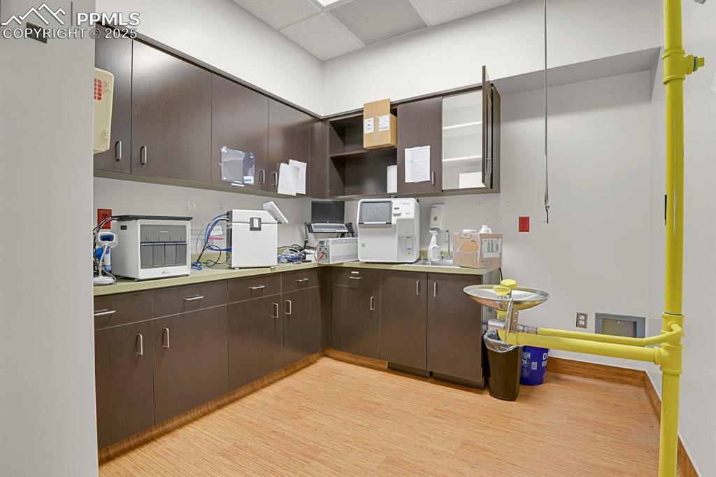 Image 27 of 50: Kitchen with open shelves, light wood-style flooring, dark brown cabinetry,