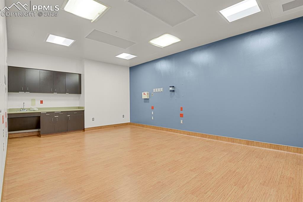 Image 30 of 50: Empty room with light wood finished floors and bar area