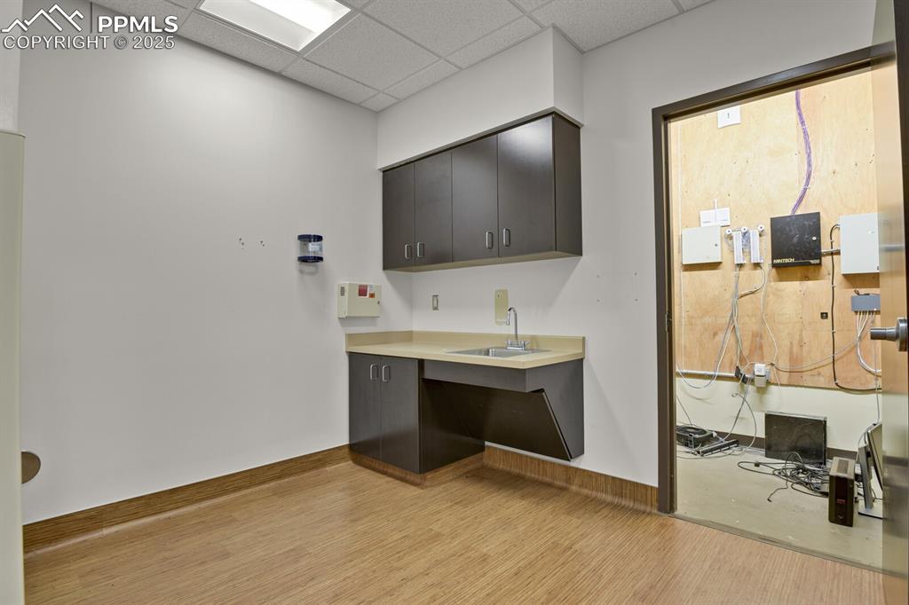 Image 33 of 50: Kitchen with light wood-style floors, a drop ceiling, light countertops, an