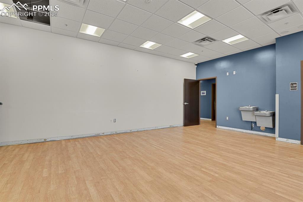 Image 8 of 50: Unfurnished room featuring a drop ceiling and wood finished floors