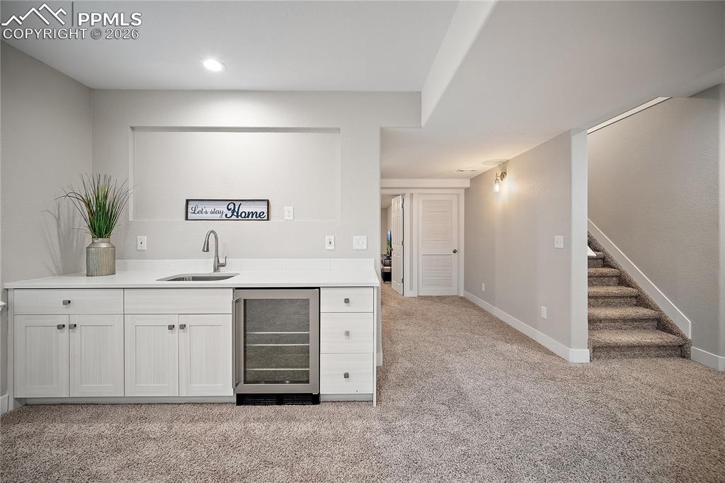 Image 36 of 46: Basement wet bar with sink and beverage fridge. 